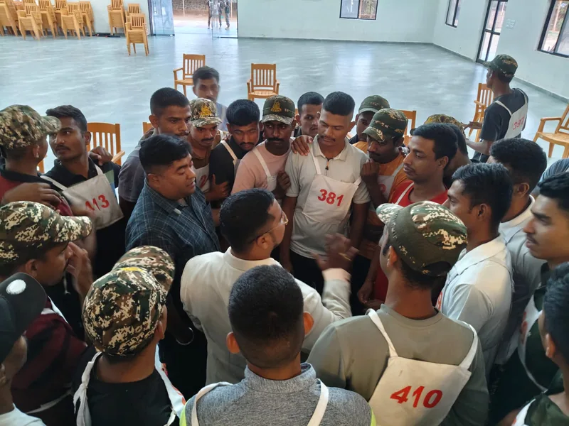 Personnel in camouflage caps and numbered training bibs gathered in conversation after a session